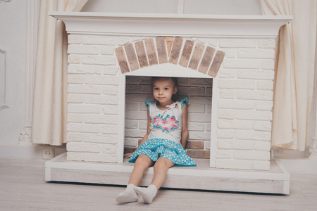 a little girl in a dress sitting inside the fireplaceの写真素材