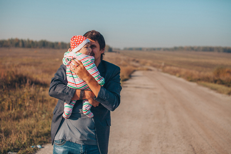 A man with a child in his arms on the road in the middle of a wastelandの写真素材