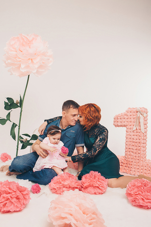 Family sitting on the floor among the flowers on a white background.の写真素材