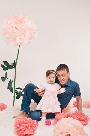Family portrait: a man and a child sitting on the floor among the flowers on a white backgroundの写真素材