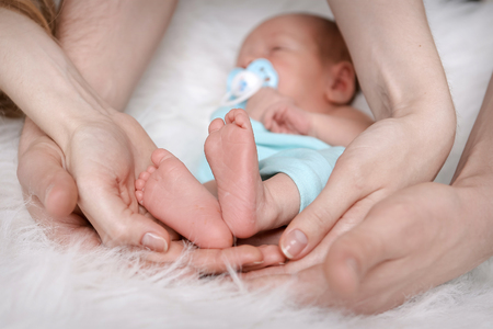 the baby sleeps on his back at the hands of parents on a white backgroundの写真素材