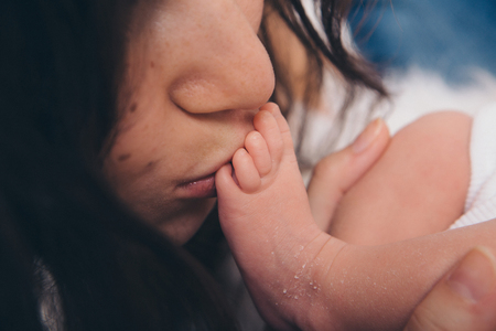 Close-up photo: a woman kissing a baby legの写真素材