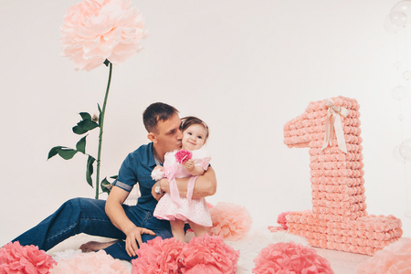 Family portrait: a man and a child sitting on the floor among the flowers on a white backgroundの写真素材