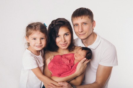 Family portrait on white background: newborn baby surrounded by man, woman and girlの写真素材