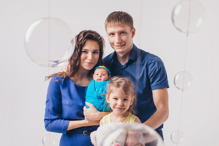 Family portrait on white background: newborn baby surrounded by man, woman and girlの写真素材