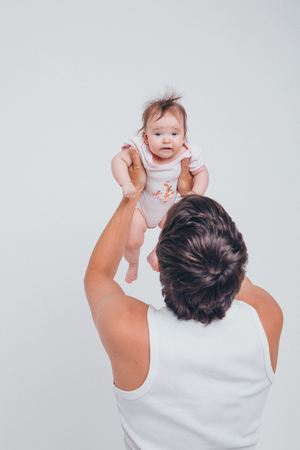 Dad raised his daughter in his arms on a white background. Girl in flyの写真素材