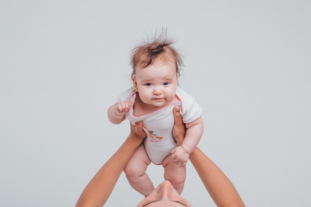 Dad raised his daughter in his arms on a white background. Girl in flyの写真素材