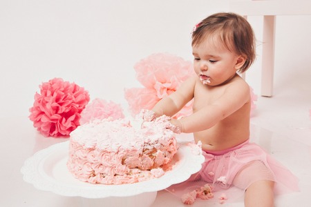 little baby girl eating pimk cake isolated white backgroundの写真素材