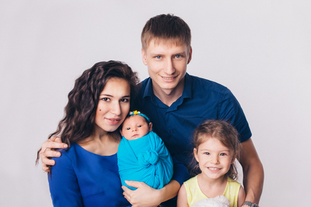 Family portrait on white background: newborn baby surrounded by man, woman and girlの写真素材