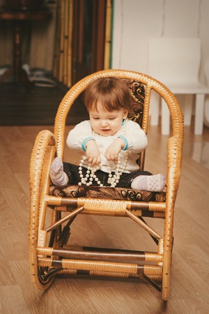 A little girl playing with a beads sitting in a chairの写真素材