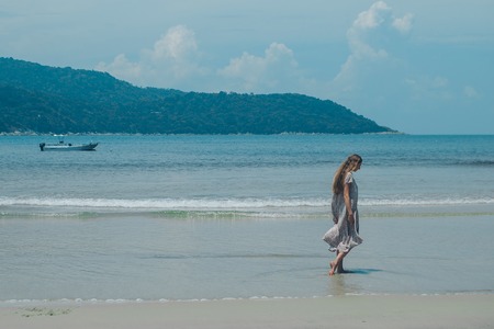 handsome girl on the beach background. Portrait of a woman in white clothes on the seaの写真素材