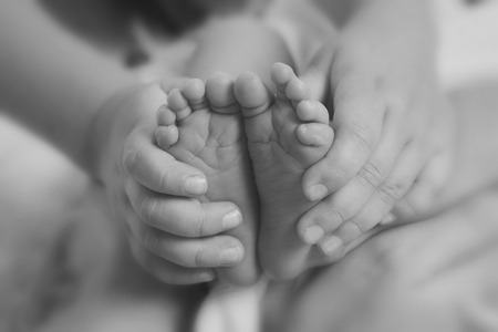 Newborn Baby's feet.Mother holding newborn baby legs,legs massageの写真素材