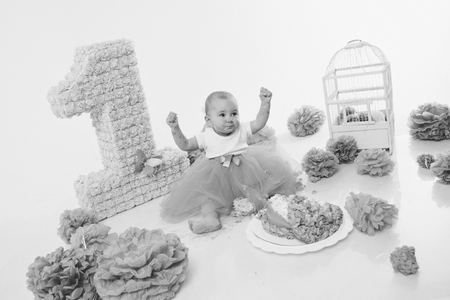 a little girl eats cake with her hands. The baby was covered in food. isolated white background. birthday partyの写真素材