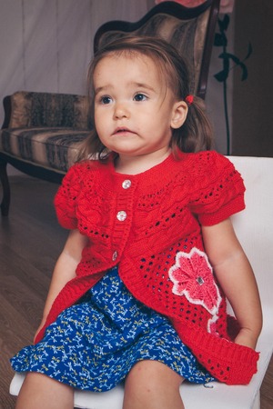 little girl in red and blue clothes sitting on the chairの写真素材