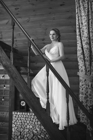 a woman in a white dress leaned against the railing of the stairsの写真素材