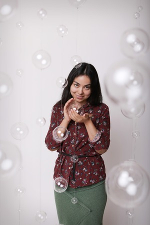 beautiful girl among the glass balls one of which she holds in her handsの写真素材
