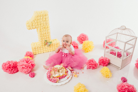 a little girl eats cake with her hands. The baby was covered in food. isolated white background. birthday partyの写真素材