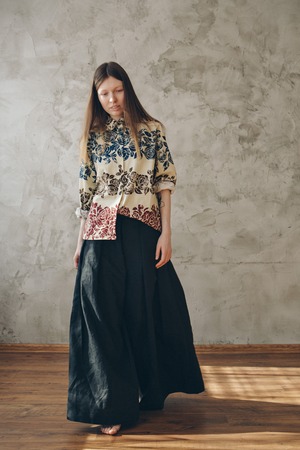 the model advertises a beige shirt with a free cut with flowers and wide black pants in Japanese...