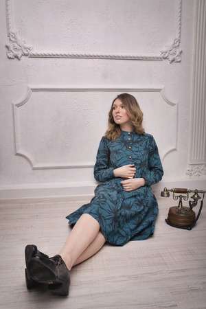 beautiful girl model in blue dress in retro style next to vintage phoneの写真素材