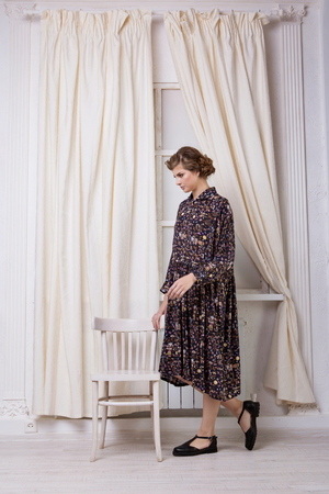 beautiful girl model stands in a dress in a flower free cut by the window on a white backgroundの写真素材
