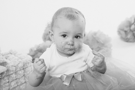 a little girl eats cake with her hands. The baby was covered in food. isolated white background. birthday partyの写真素材
