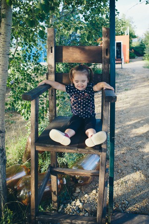 Cute little girl with big wooden chair in studioの写真素材