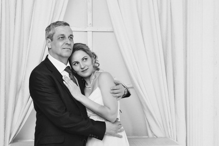 Wedding couple on the nature is hugging each other. Beautiful model girl in white dress. Man in suit. Beauty bride with groom. Female and male portrait. Woman with lace veil. Lady and guy outdoorsの写真素材
