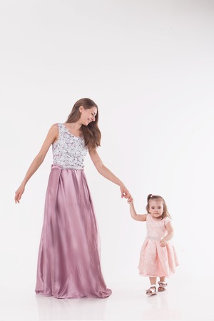 mother and child posing on a white background. Woman and girl in pink dress playの写真素材