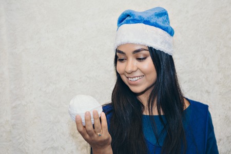 a girl in a blue Christmas suit with snowballs in her hands. Beautiful Asian woman posing with a white ball of threadの写真素材