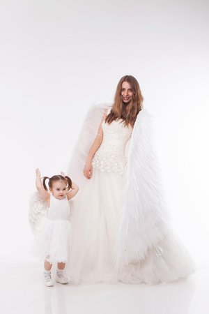 a woman and a girl in white dresses with angel wings on his back. Big and small angel on white backgroundの写真素材