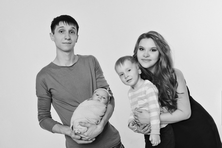 Family portrait on white background: newborn baby surrounded by man, woman and boyの写真素材