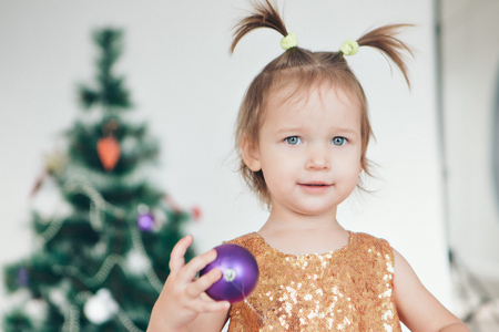 a little girl in a dress adorns the Christmas tree on a white backgroundの写真素材