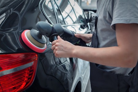 polishing machine on the surface of the black car close-up