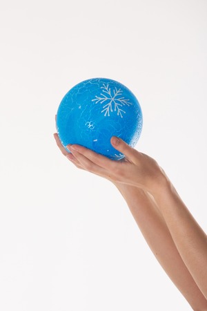 hands close-up on white background: woman holding blue Christmas ball with snowflake patternの写真素材