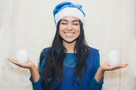 a girl in a blue Christmas suit with snowballs in her hands. Beautiful Asian woman posing with a white ball of threadの写真素材