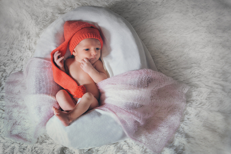 a naked newborn baby sleeps in a Christmas hat.の写真素材