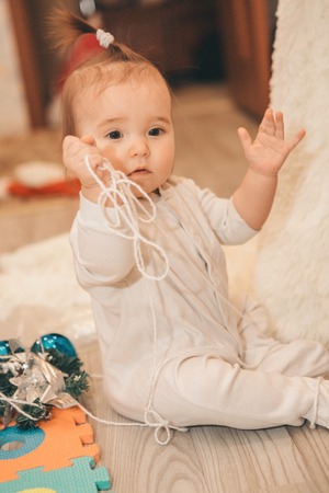 little girl playing on the floor with threads and Christmas toysの写真素材