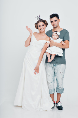 a little girl in the hands of the Prince and Princess. a man and a woman in suits holding a child in their armsの写真素材
