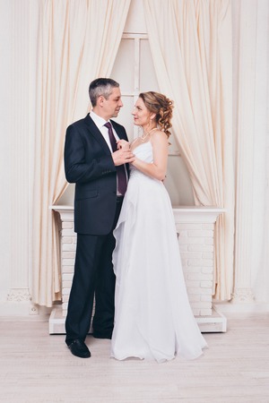 Wedding couple on the nature is hugging each other. Beautiful model girl in white dress. Man in suit. Beauty bride with groom. Female and male portrait. Woman with lace veil. Lady and guy outdoorsの写真素材