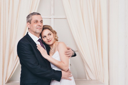 Wedding couple on the nature is hugging each other. Beautiful model girl in white dress. Man in suit. Beauty bride with groom. Female and male portrait. Woman with lace veil. Lady and guy outdoorsの写真素材