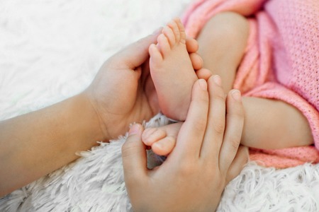 Newborn Baby's feet.Mother holding newborn baby legs,legs massageの写真素材