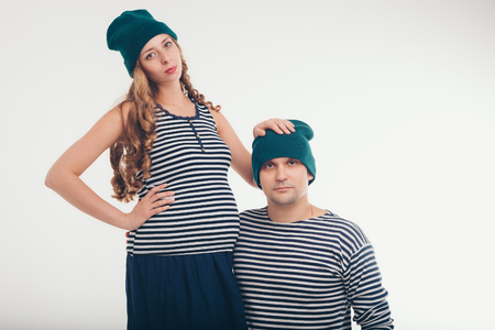 couple husband and wife: man and pregnant woman in vests and green hats on white backgroundの写真素材