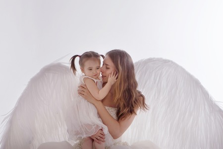 a woman and a girl in white dresses with angel wings on his back. Big and small angel on white backgroundの写真素材