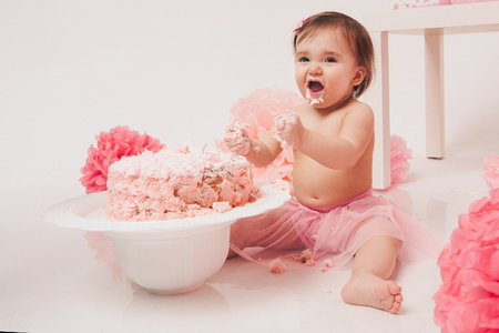 little baby girl eating pimk cake isolated white backgroundの写真素材