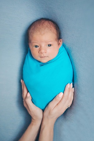 portrait of newborn baby lying on the hands of parents on a blue backgroundの写真素材