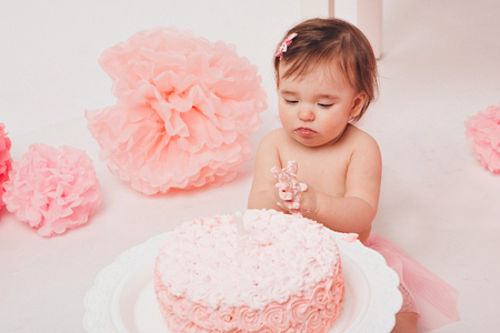 little baby girl eating pimk cake isolated white backgroundの写真素材