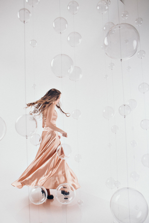 beautiful long-haired girl in long dress dancing on white backgroundの写真素材