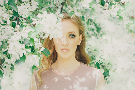 beautiful girl model with bright makeup among white flowers. Portrait of a woman close-upの写真素材