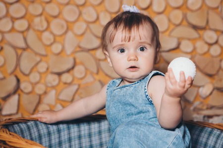 a small child sitting in the basket with a Christmas ball in his handsの写真素材