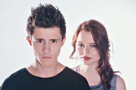 Cropped image of beautiful couple looking at the camera standing straight on white backgroundの写真素材